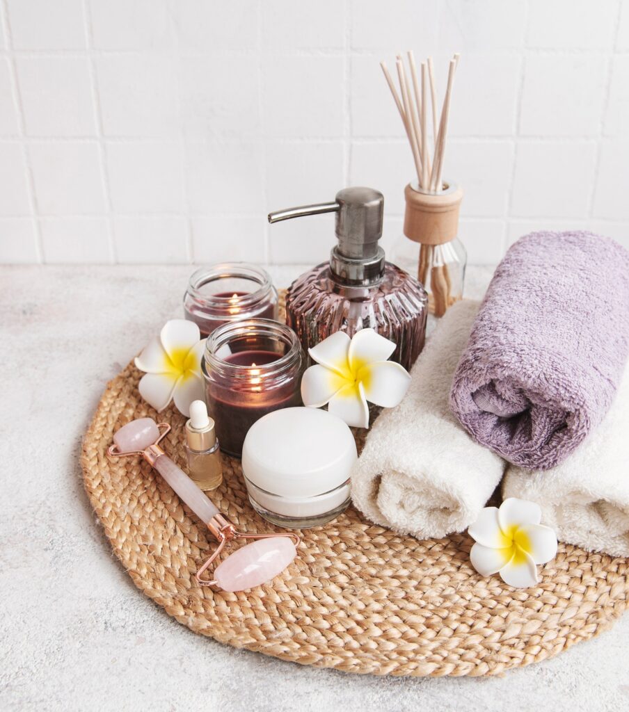 Spa set, essential oil, massage salt, candle and frangipani flowers on gray concrete background